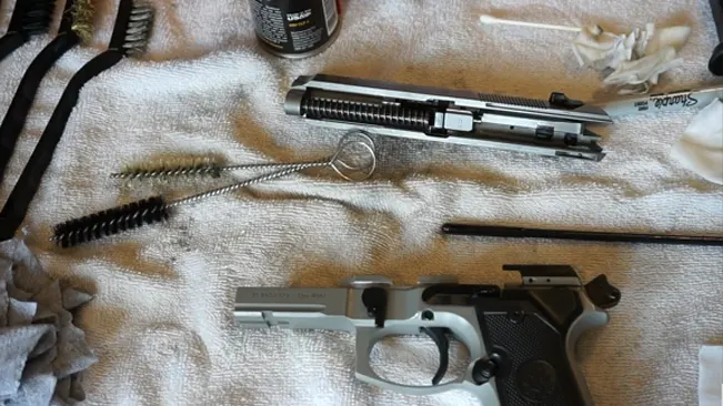 Disassembled Beretta 92FS INOX on a towel with cleaning brushes and gun maintenance supplies.