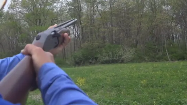 First-person view of hands holding a Mossberg 930 shotgun aiming outdoors