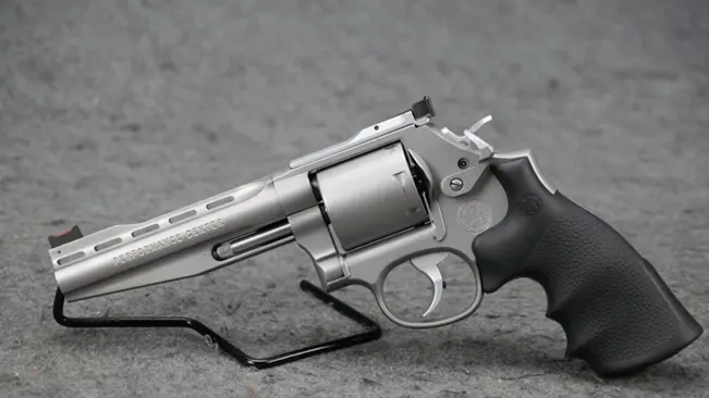 Smith & Wesson 686 revolver with a vented barrel and adjustable sights, resting on a stand against a grey background.