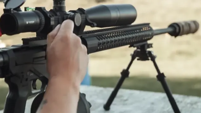 Person aiming a Ruger Precision Rifle with a scope, mounted on a bipod
