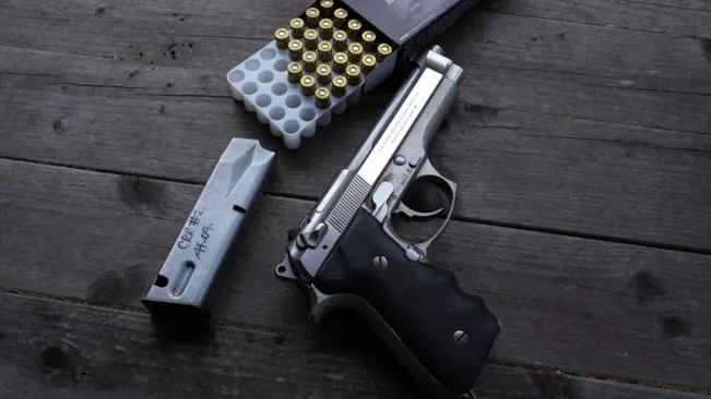 Beretta 92FS INOX with magazine and 9mm ammunition on a wooden table.