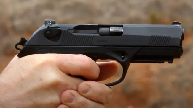 Hand gripping a Beretta PX4 Storm subcompact pistol, ready to fire with sights aligned.