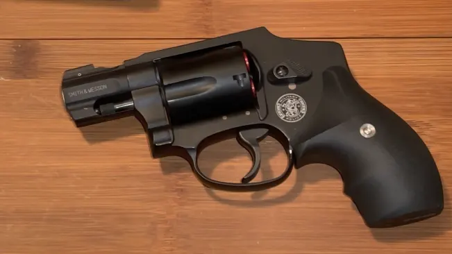 A Smith & Wesson J-Frame 340 PD revolver with a black finish on a wooden surface.