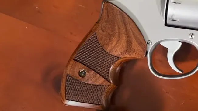 Detail of the wooden grip on a Smith & Wesson 627 revolver with textured patterns.