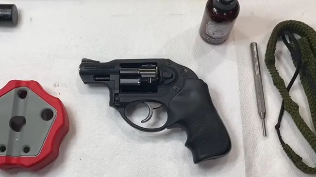 Ruger LCR revolver on a white surface with cleaning supplies and tools.