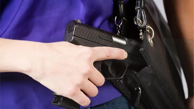 a woman getting her concealed carry gun on her bag