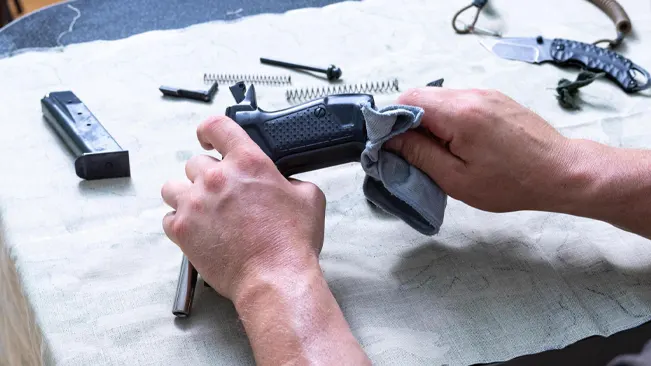 a hand of a person maintaining and  cleaning its gun