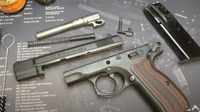 A disassembled CZ 75 B handgun laid out on a mat with labeled sections for parts, including the barrel, slide, and magazine, with a focus on the detailed disassembly process.