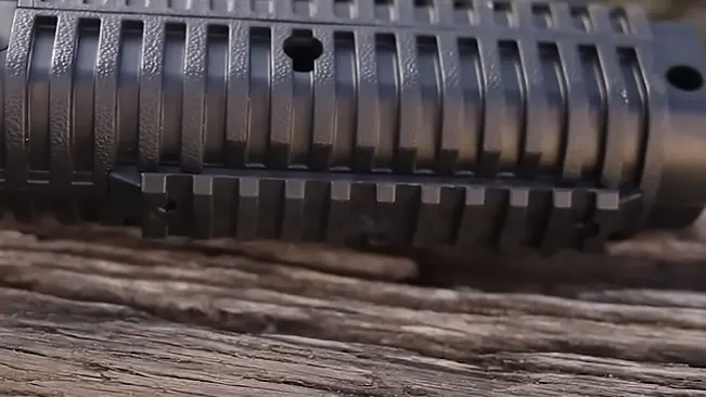 Close-up of a textured rifle barrel shroud on a wooden surface.
