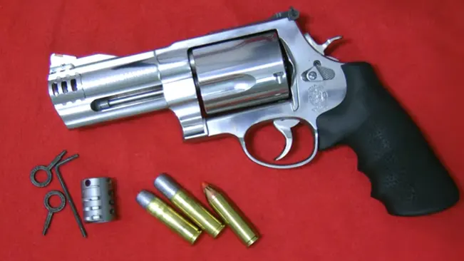 Smith & Wesson Model 500 revolver with ammunition and speed loader on a red background.