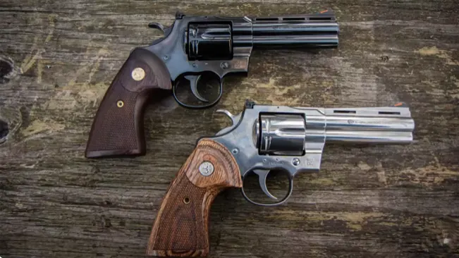 Two Colt Python revolvers, one blued and one stainless, with wooden grips on a rustic wooden background.
