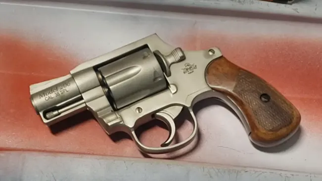 Rock Island M206 Spurless Matte revolver with wooden grips on a red surface.