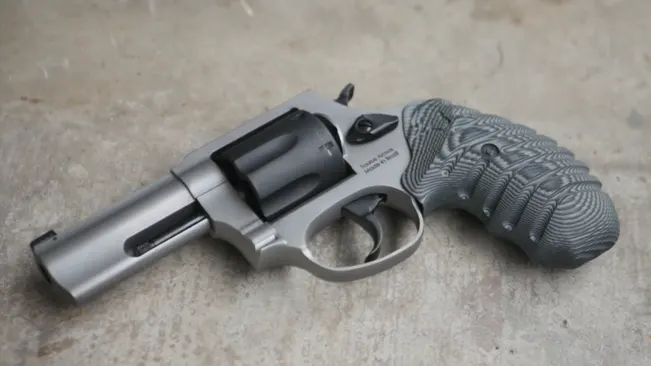 Taurus Defender 856 revolver with a matte stainless finish and engraved grips on a concrete surface.