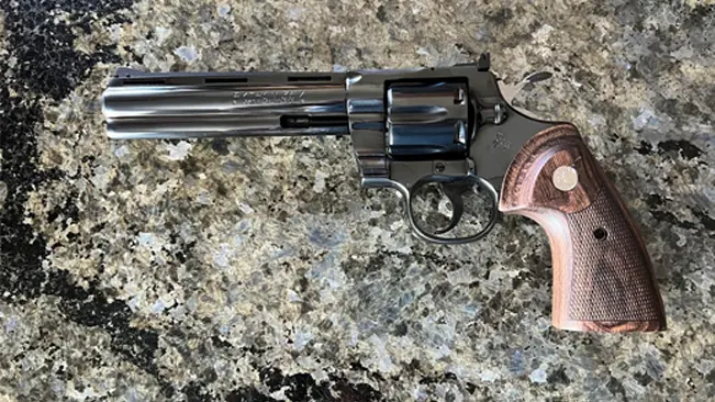 Colt Blued Python revolver with checkered wooden grips on a granite surface.