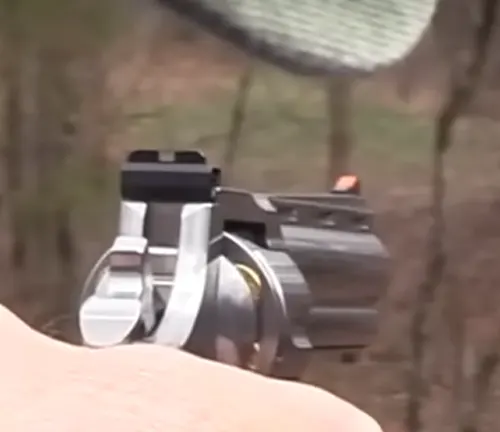 Rear view of a Colt Python 6-inch revolver sighted on a target, with a focus on the rear sight and blurred background.