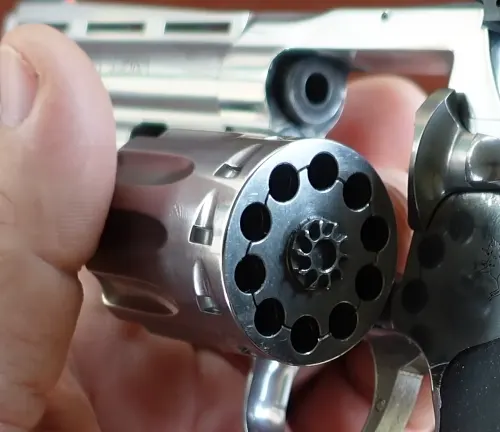 Close-up of an open cylinder of a King Cobra Target .22 revolver held in a hand.