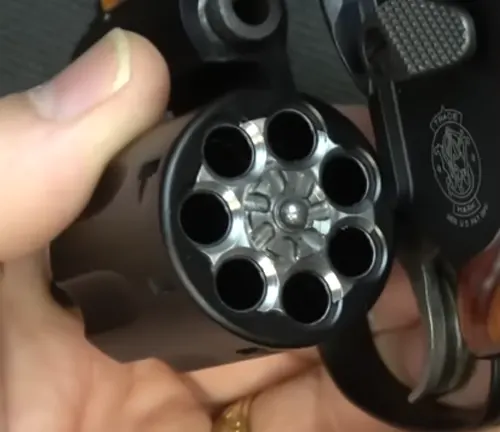 Hand holding a Smith & Wesson Model 351 PD revolver, showing an open and empty cylinder.