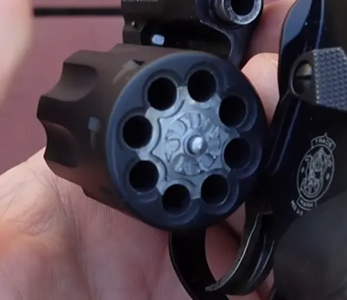 Close-up of a hand holding a Smith & Wesson Model 43C revolver with an open cylinder.