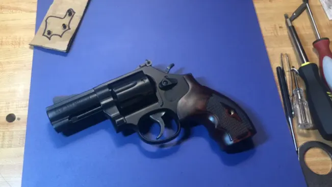 Alt text: "Smith & Wesson Model 586 revolver on a blue mat next to gunsmithing tools.