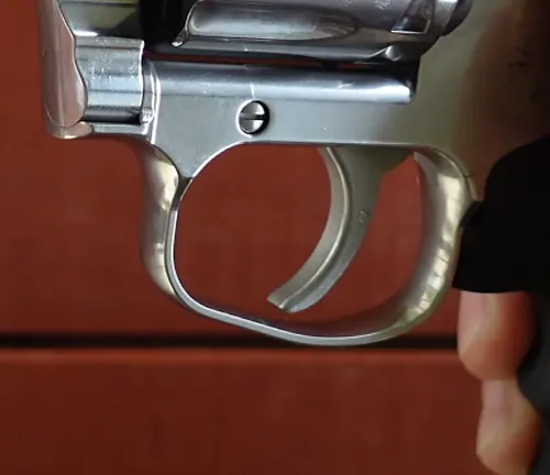 Close-up of the trigger and trigger guard of a King Cobra Target .22 revolver with a stainless finish.