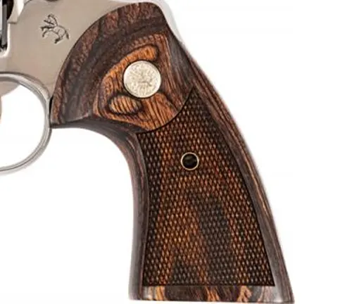 Detailed view of a Colt Python 6-inch revolver's wooden grip with checkered pattern and silver Colt medallion.