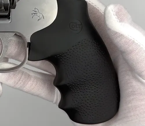 Close-up of the black Hogue grip with the Colt logo on a King Cobra Carry revolver, held with a gloved hand.
