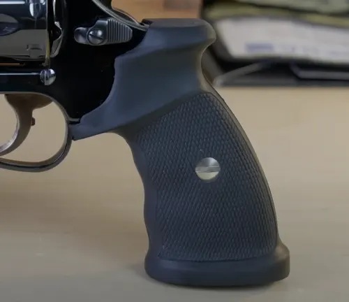 Black textured grip of a Manurhin MR73 revolver with a silver emblem.