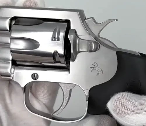 Close-up of a King Cobra Carry revolver's cylinder and trigger, with a gloved hand and the Colt logo visible.