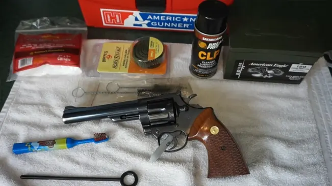 Colt Trooper MK III revolver on a white towel with cleaning supplies and ammunition boxes.